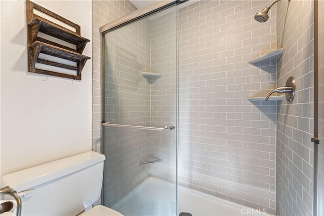 bathroom featuring toilet and a shower with shower door