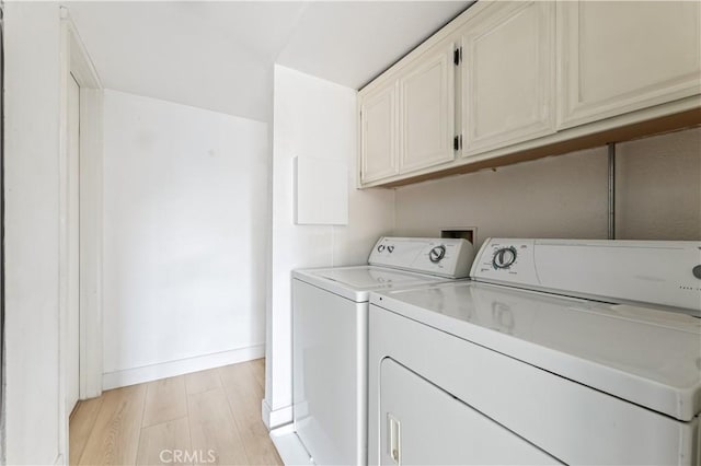 washroom with cabinets, independent washer and dryer, and light hardwood / wood-style flooring