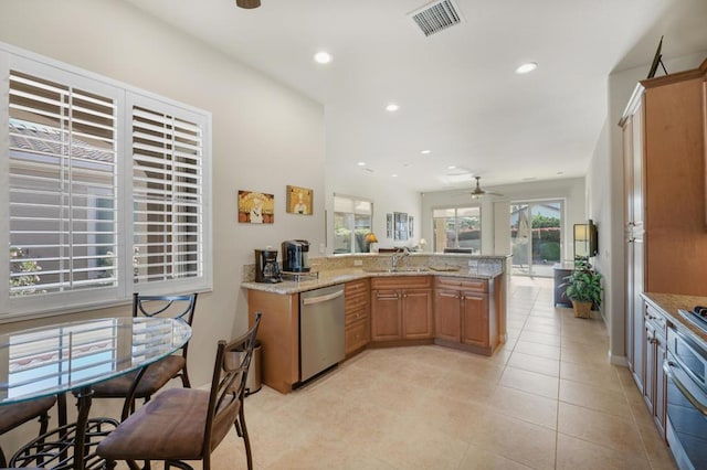 kitchen featuring ceiling fan, dishwasher, sink, light stone counters, and kitchen peninsula