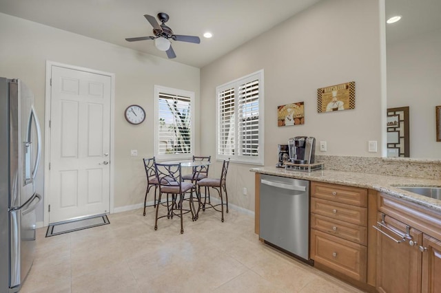 kitchen with ceiling fan, light stone counters, light tile patterned floors, and appliances with stainless steel finishes