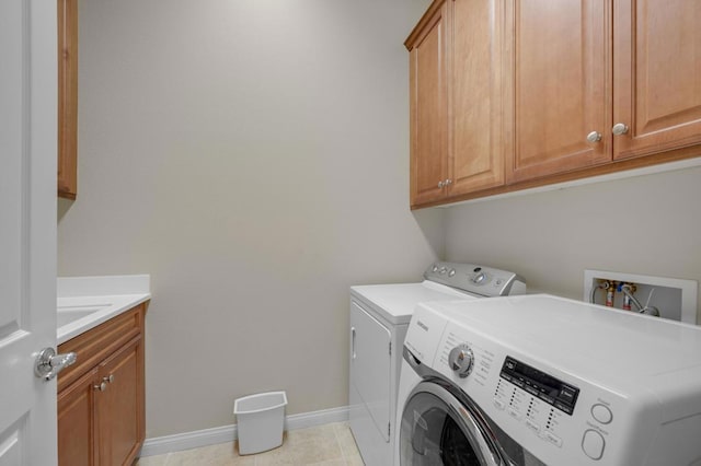 laundry area featuring washer and clothes dryer, light tile patterned floors, and cabinets