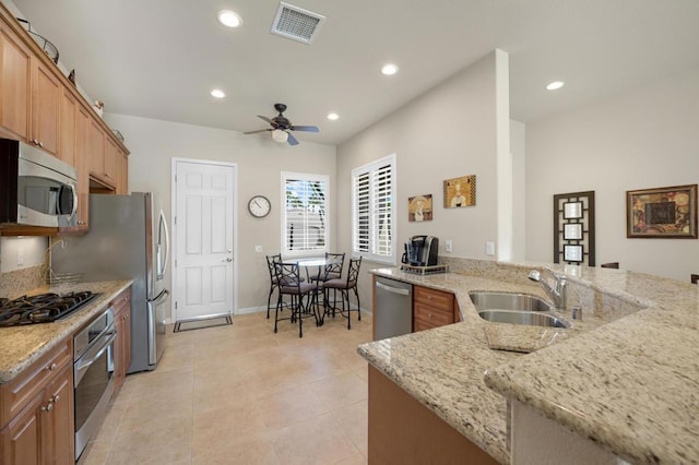 kitchen with kitchen peninsula, light stone countertops, sink, and stainless steel appliances