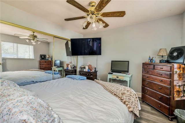 bedroom with light wood-type flooring, vaulted ceiling, a closet, and ceiling fan