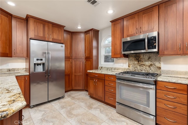 kitchen with light tile patterned flooring, light stone counters, stainless steel appliances, and tasteful backsplash