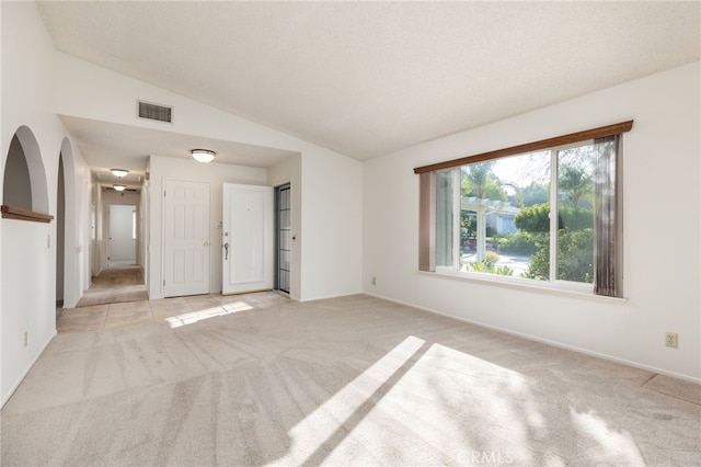 carpeted empty room featuring a textured ceiling and vaulted ceiling