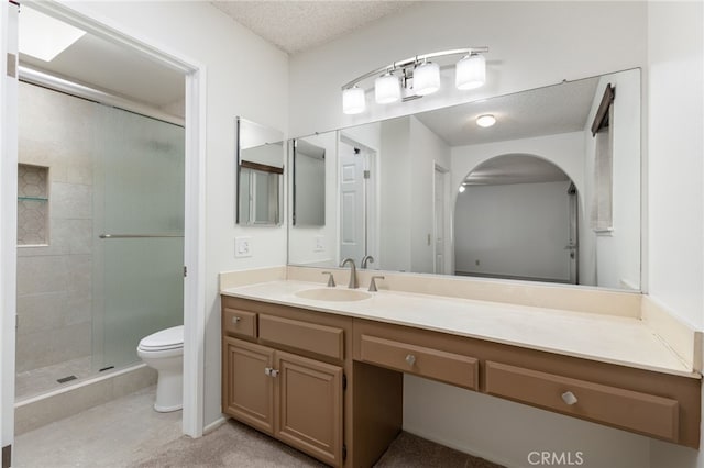 bathroom with walk in shower, vanity, a textured ceiling, and toilet