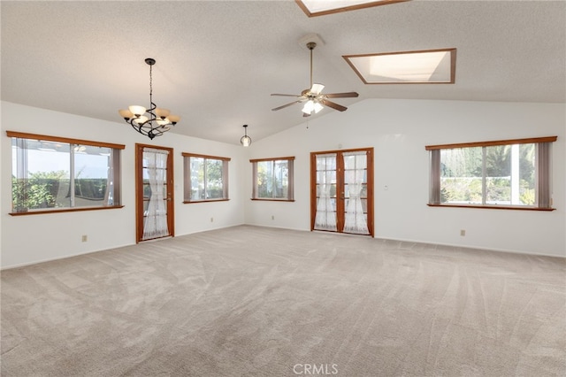 carpeted spare room with a textured ceiling, ceiling fan with notable chandelier, a wealth of natural light, and lofted ceiling