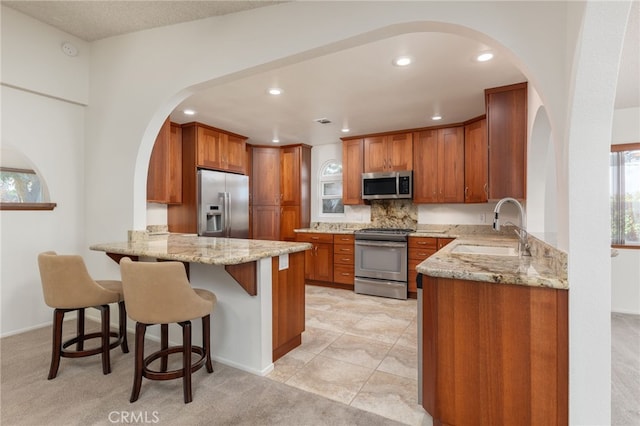 kitchen with sink, kitchen peninsula, stainless steel appliances, and light carpet