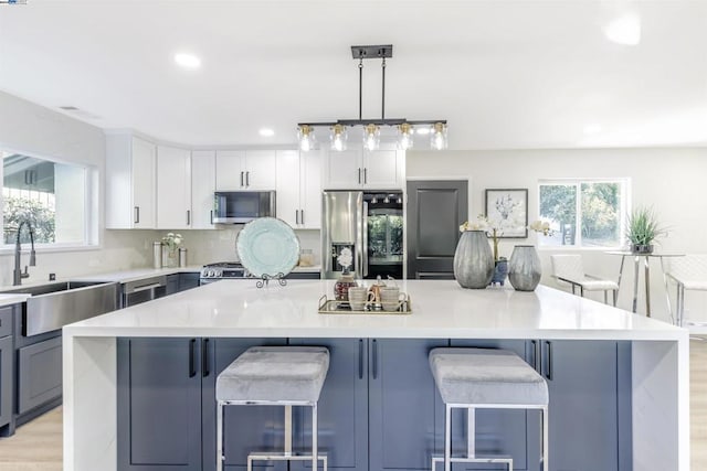 kitchen with a kitchen breakfast bar, stainless steel appliances, a large island, and a healthy amount of sunlight