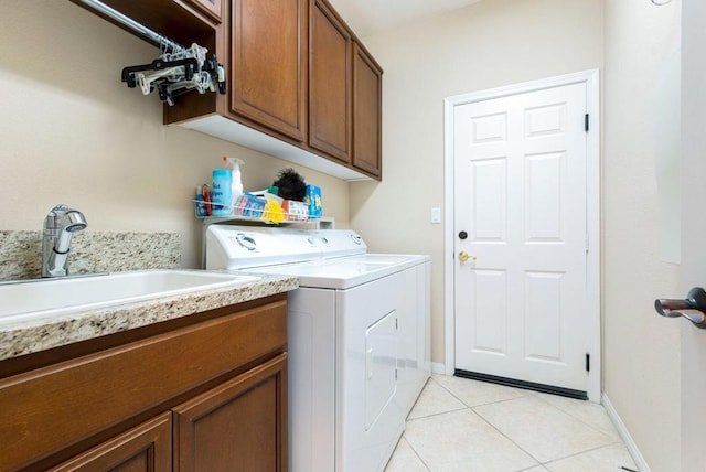 clothes washing area featuring separate washer and dryer, sink, light tile patterned floors, and cabinets