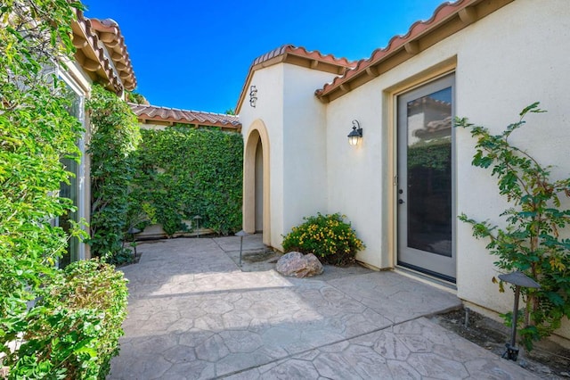 view of exterior entry with a patio