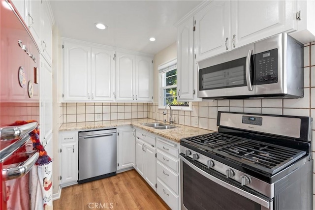 kitchen featuring sink, decorative backsplash, appliances with stainless steel finishes, light hardwood / wood-style floors, and white cabinetry