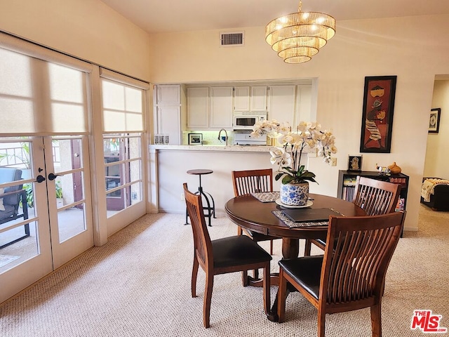 dining room with french doors, an inviting chandelier, and light carpet