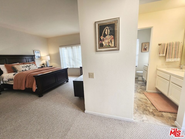 carpeted bedroom with sink and ensuite bath