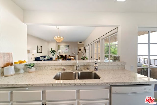 kitchen with sink, an inviting chandelier, hanging light fixtures, white dishwasher, and light stone counters