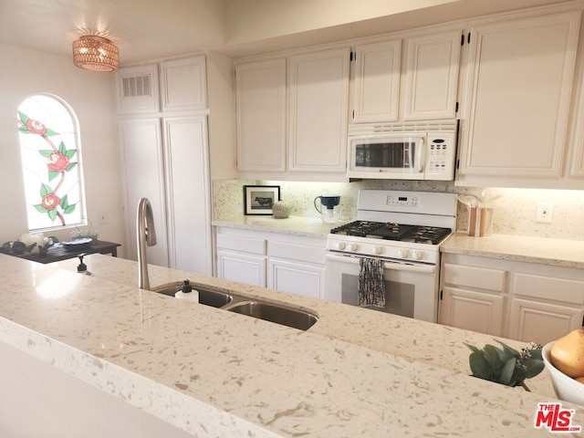 kitchen featuring sink, white appliances, light stone countertops, and white cabinets