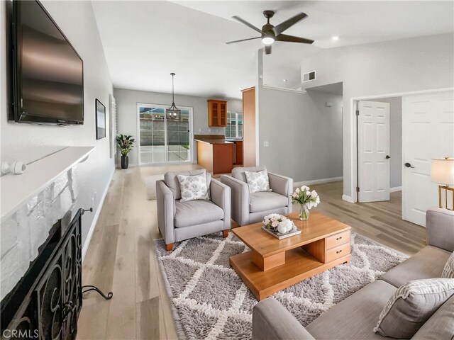 living room featuring a fireplace, light hardwood / wood-style flooring, and ceiling fan