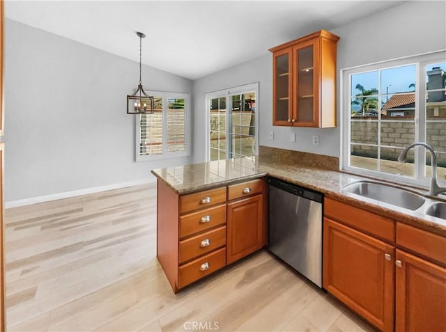 kitchen with hanging light fixtures, dishwasher, stone counters, sink, and kitchen peninsula