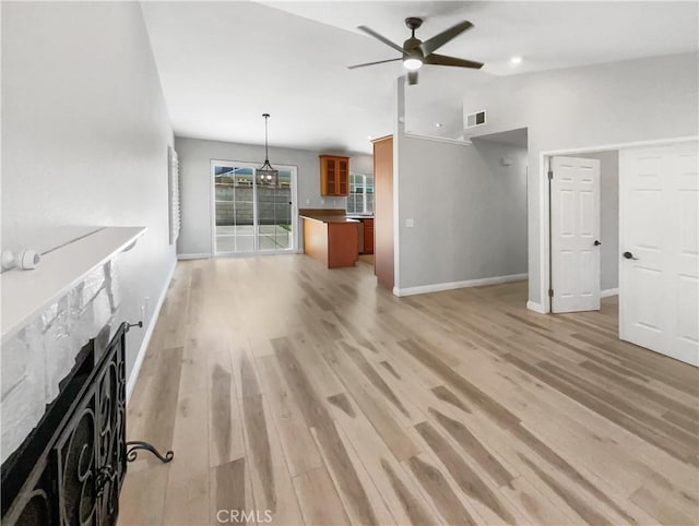 unfurnished living room with a tile fireplace, ceiling fan, and light hardwood / wood-style floors