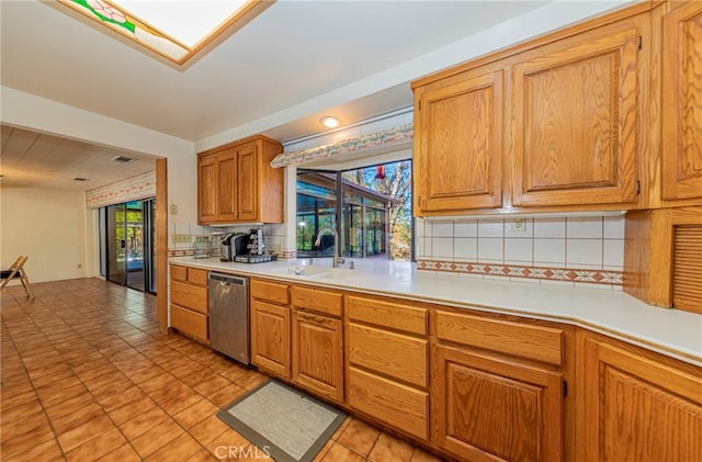 kitchen with stainless steel dishwasher, a wealth of natural light, light countertops, and a sink