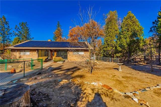 view of front of property with fence, solar panels, and brick siding