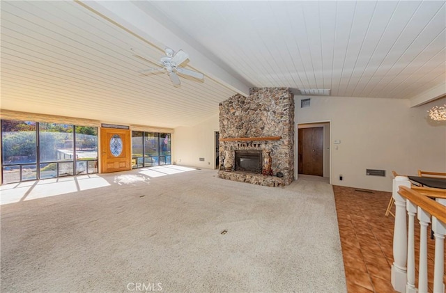 unfurnished living room with carpet floors, vaulted ceiling with beams, ceiling fan, a stone fireplace, and tile patterned floors