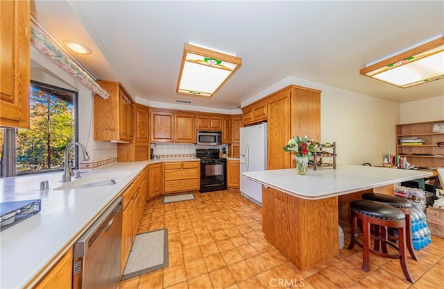 kitchen featuring stainless steel appliances, a sink, light countertops, tasteful backsplash, and a kitchen bar