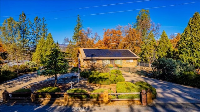 view of front of house with fence and solar panels