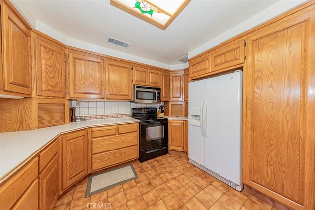 kitchen with black range with electric stovetop, visible vents, light countertops, white fridge with ice dispenser, and stainless steel microwave