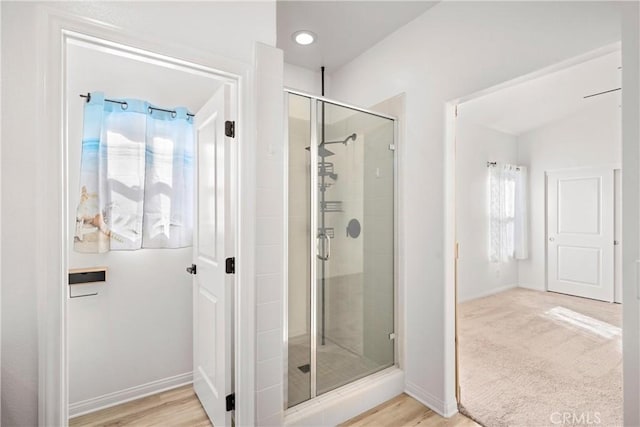 bathroom with hardwood / wood-style flooring and a shower with door