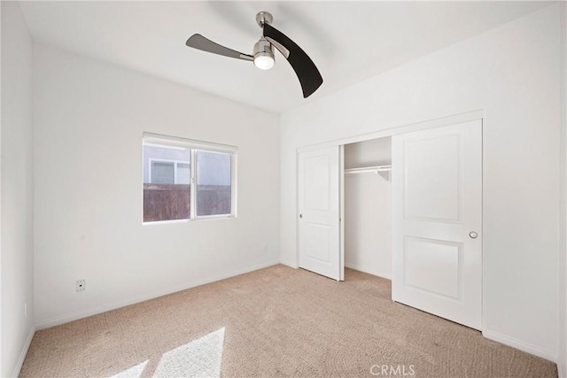 unfurnished bedroom with ceiling fan, a closet, and light carpet