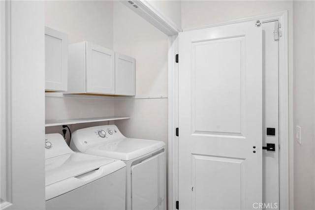 laundry room featuring separate washer and dryer and cabinets