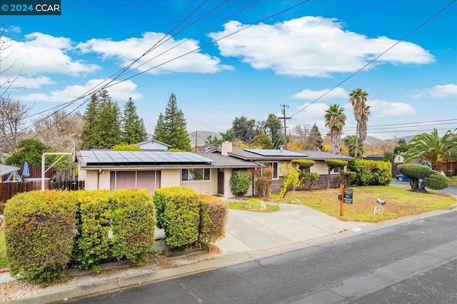 ranch-style house featuring solar panels and a front yard