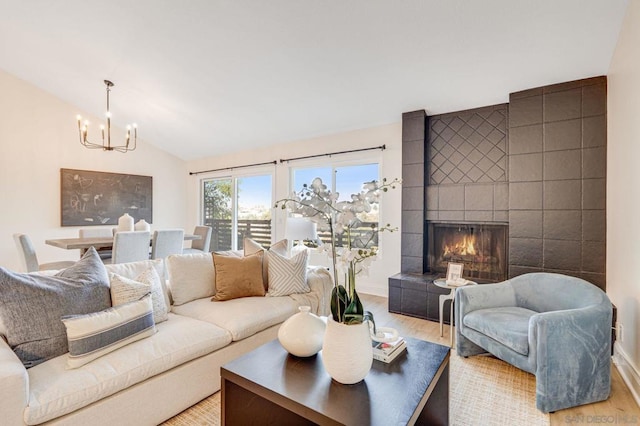 living room featuring an inviting chandelier, a fireplace, vaulted ceiling, and light hardwood / wood-style flooring