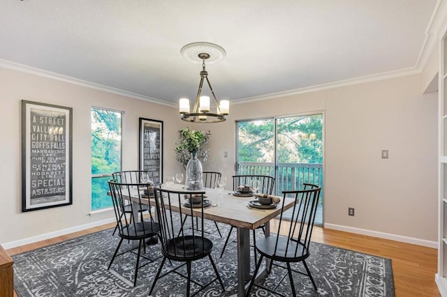 dining area with hardwood / wood-style flooring, ornamental molding, and a notable chandelier