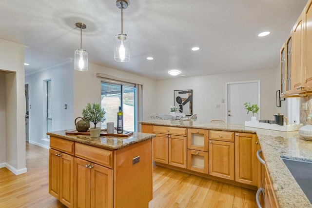 kitchen with light wood-type flooring, pendant lighting, and light stone counters