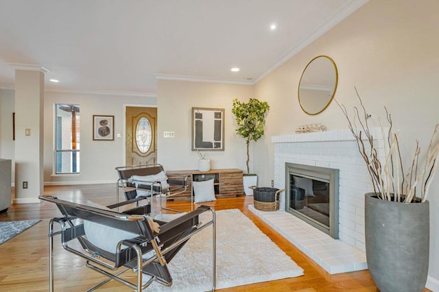 living room featuring a brick fireplace, crown molding, and light wood-type flooring