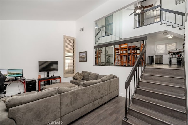 living room with ceiling fan, dark hardwood / wood-style flooring, and a towering ceiling