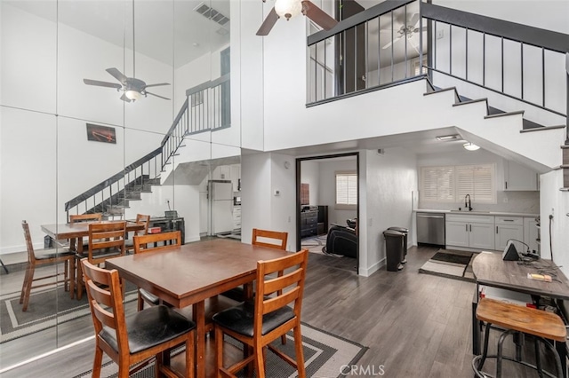 dining space featuring ceiling fan, hardwood / wood-style floors, a high ceiling, and sink