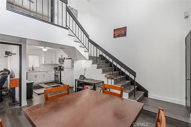 dining space with a towering ceiling, dark wood-type flooring, and sink