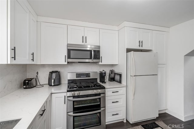 kitchen featuring light stone countertops, white cabinetry, dark wood-type flooring, and appliances with stainless steel finishes