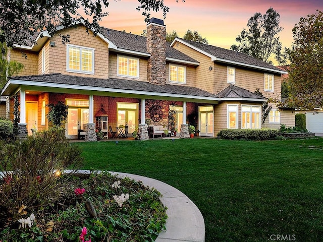 back house at dusk with a lawn