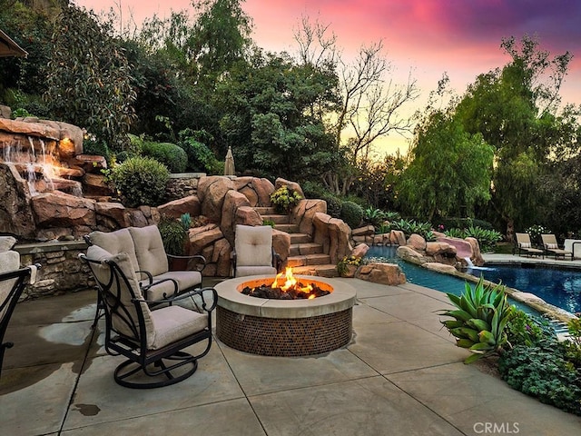 patio terrace at dusk with pool water feature and an outdoor fire pit