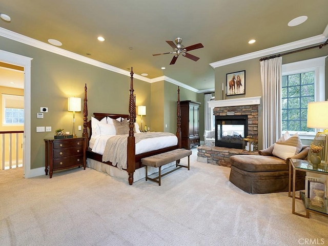 carpeted bedroom featuring a stone fireplace, crown molding, and ceiling fan