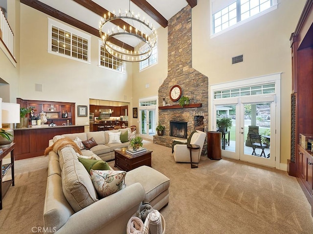 carpeted living room with beam ceiling, a towering ceiling, a wealth of natural light, and a notable chandelier