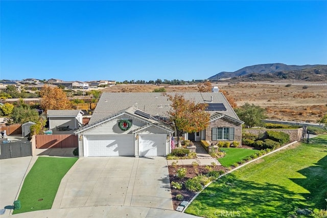 view of front of property with a mountain view, solar panels, a garage, and a front lawn