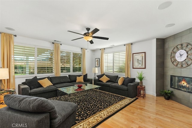 living room with hardwood / wood-style flooring, ceiling fan, and a fireplace