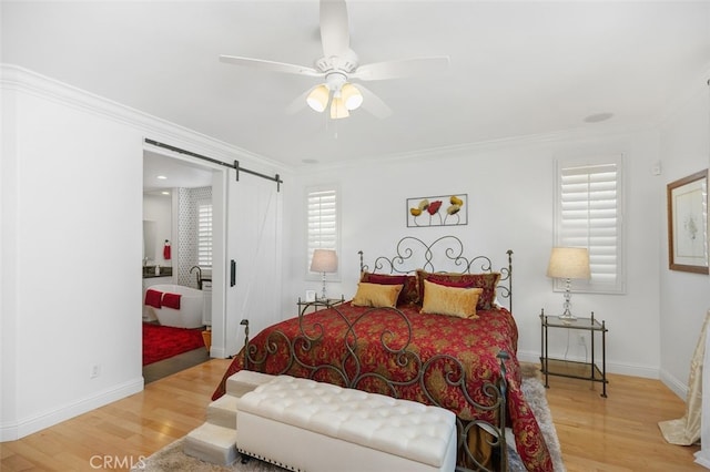 bedroom featuring ceiling fan, a barn door, crown molding, and light hardwood / wood-style flooring