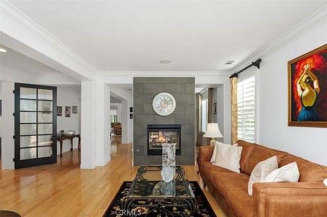 living room featuring a fireplace, ornamental molding, and light wood-type flooring