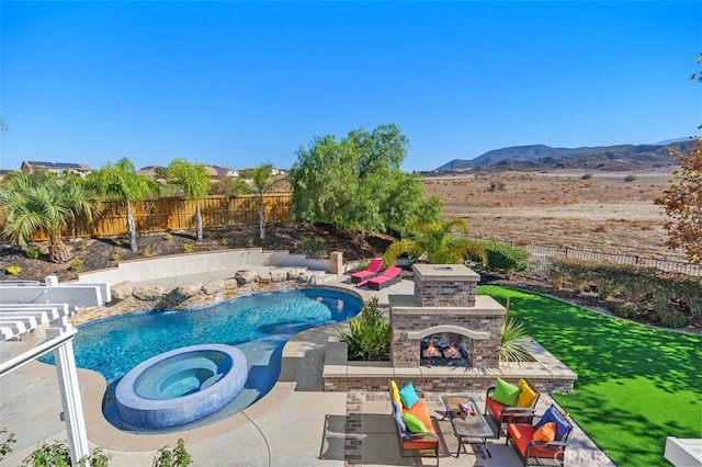 view of swimming pool with an outdoor stone fireplace, a mountain view, an in ground hot tub, and a patio